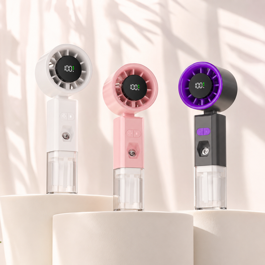 Three handheld personal fans in white, pink, and black are displayed on white pedestal stands against a softly lit background with leaf shadows. Each fan has a circular digital display, a transparent water reservoir, and a small button on the handle.