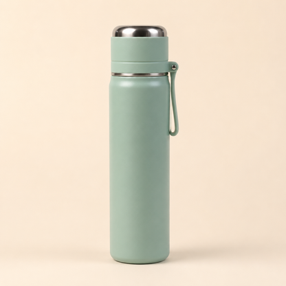 A matte sage green insulated water bottle with a stainless steel lid and a matching carrying loop, set against a solid light beige background.