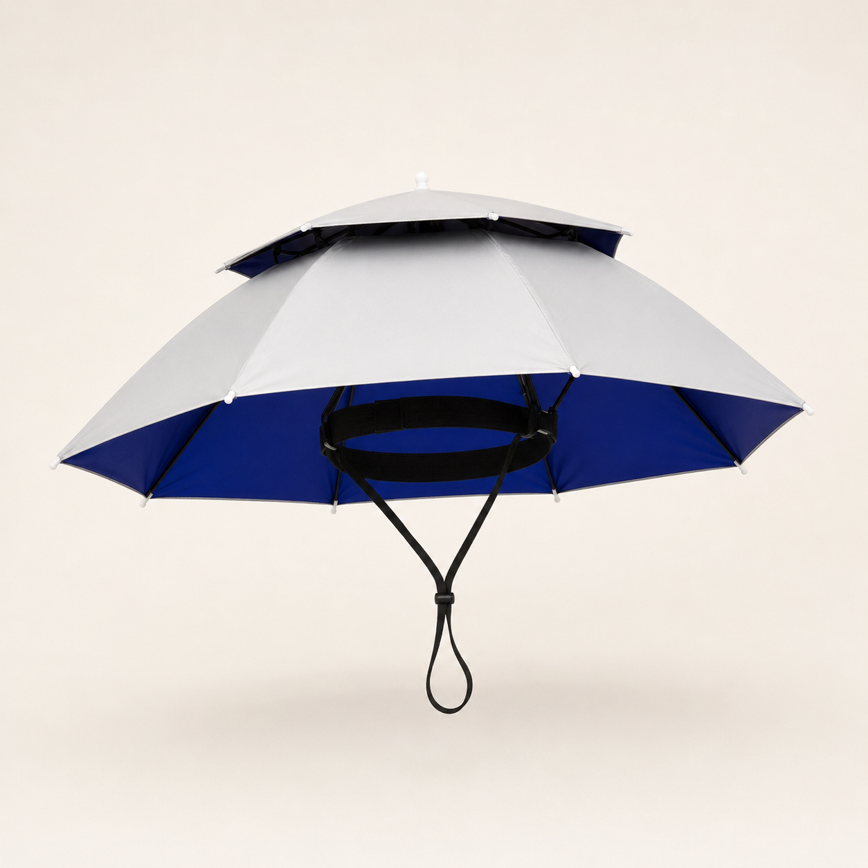 A double-tiered umbrella with a light gray upper canopy and a royal blue lower canopy, suspended by black ribs and a black carrying loop against a solid light beige background.