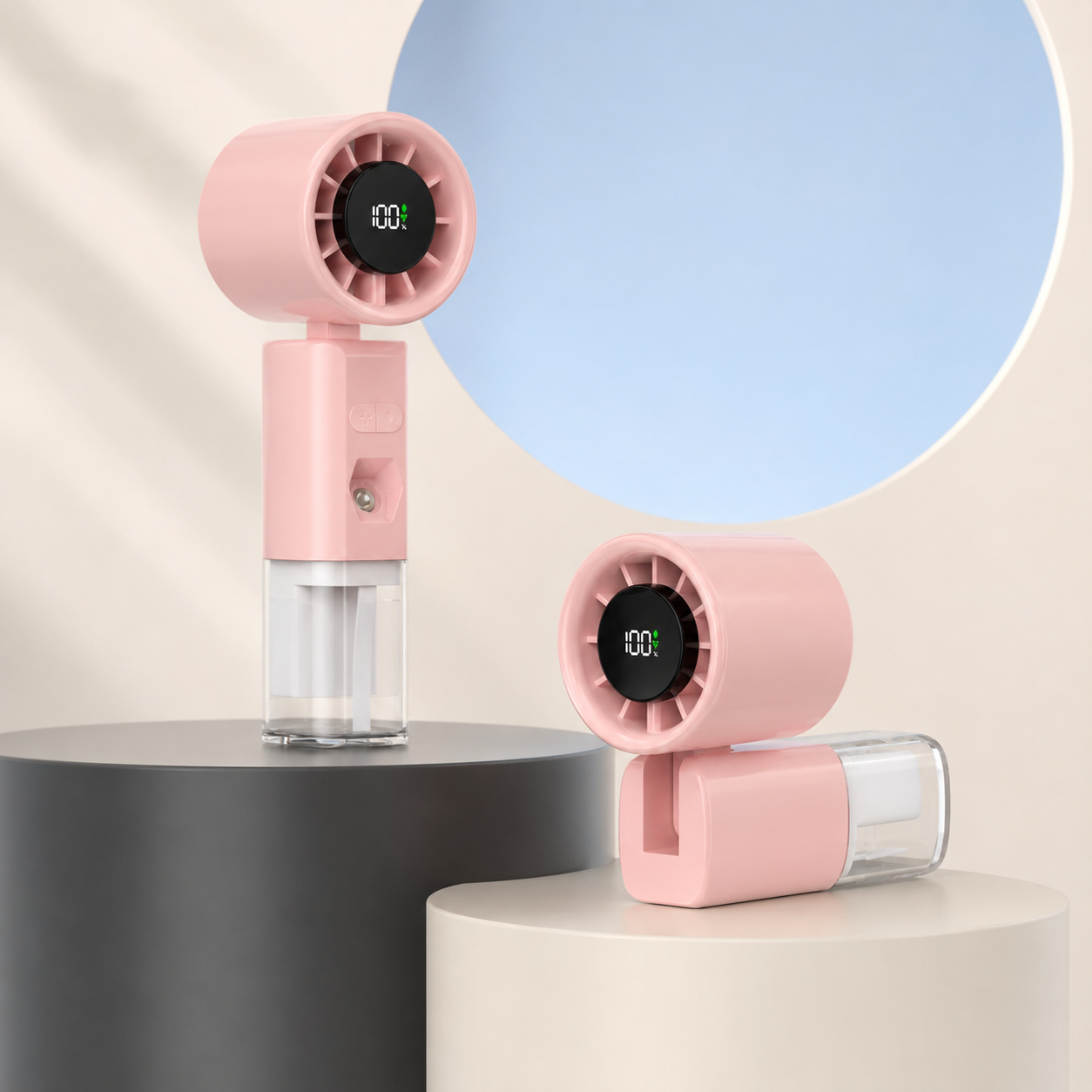 A pink handheld personal fan with a clear water bottle reservoir, shown in two positions on minimalist pedestals against a light beige background with a blue circular graphic.