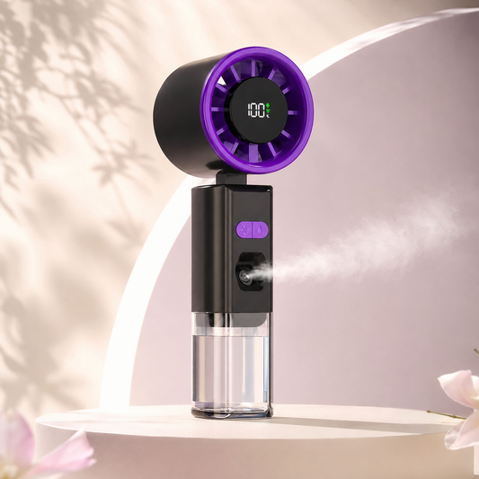 A handheld personal humidifier and fan with a black body and a purple circular fan head, shown spraying mist on a light beige studio set with soft shadows and decorative petals.